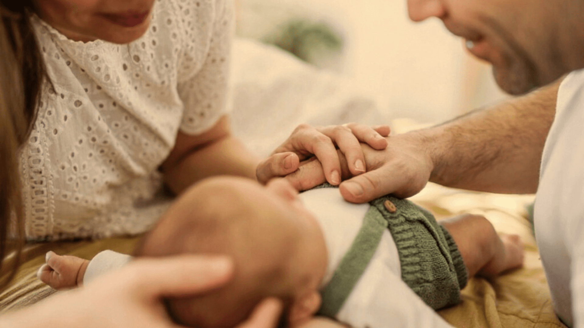 Close up image of two parents playing with their baby