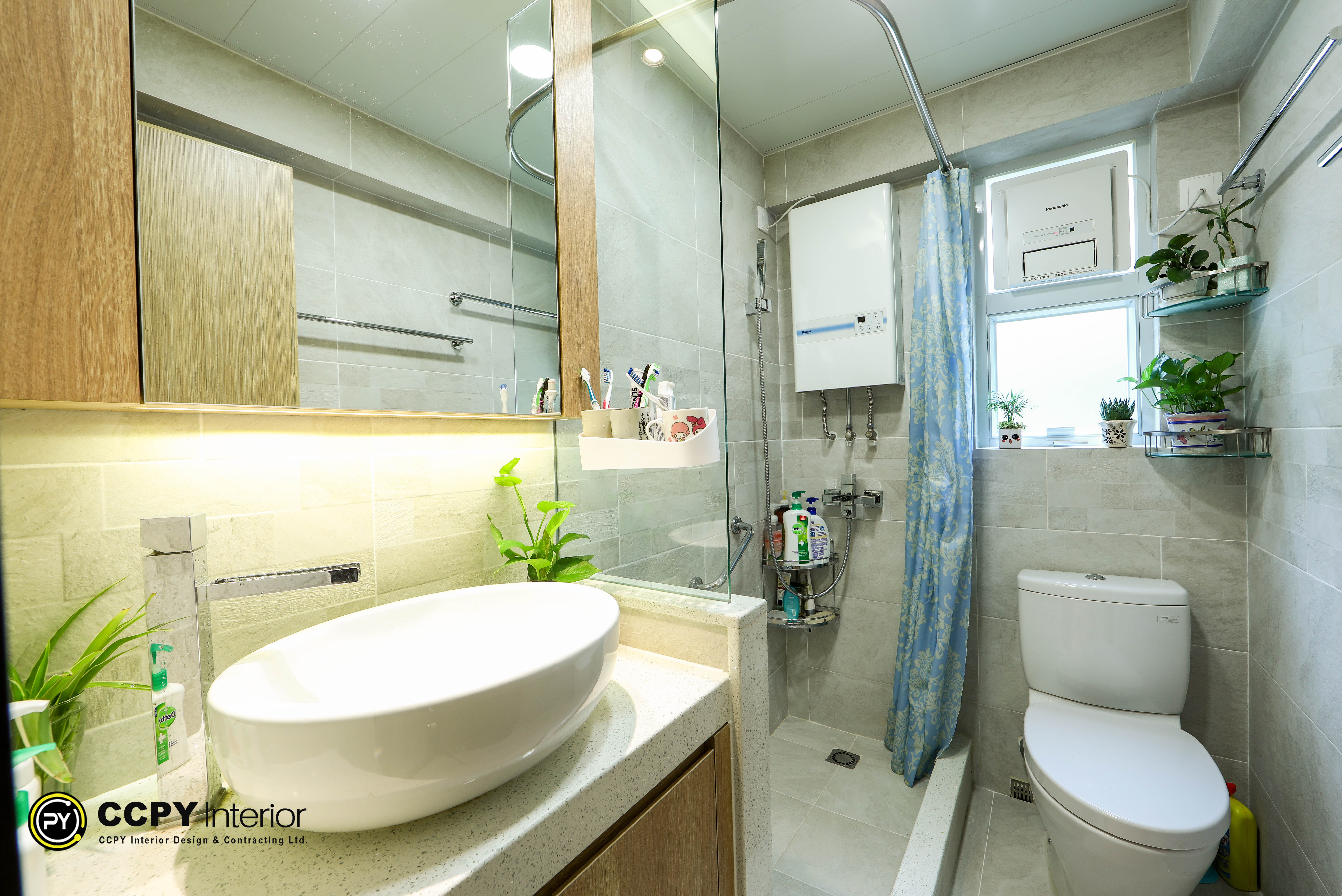 Bathroom sink area with wooden veneer door, matte black coat hooks, and a warm-lit mirror cabinet at Kwan Lok Sun Chuen.
