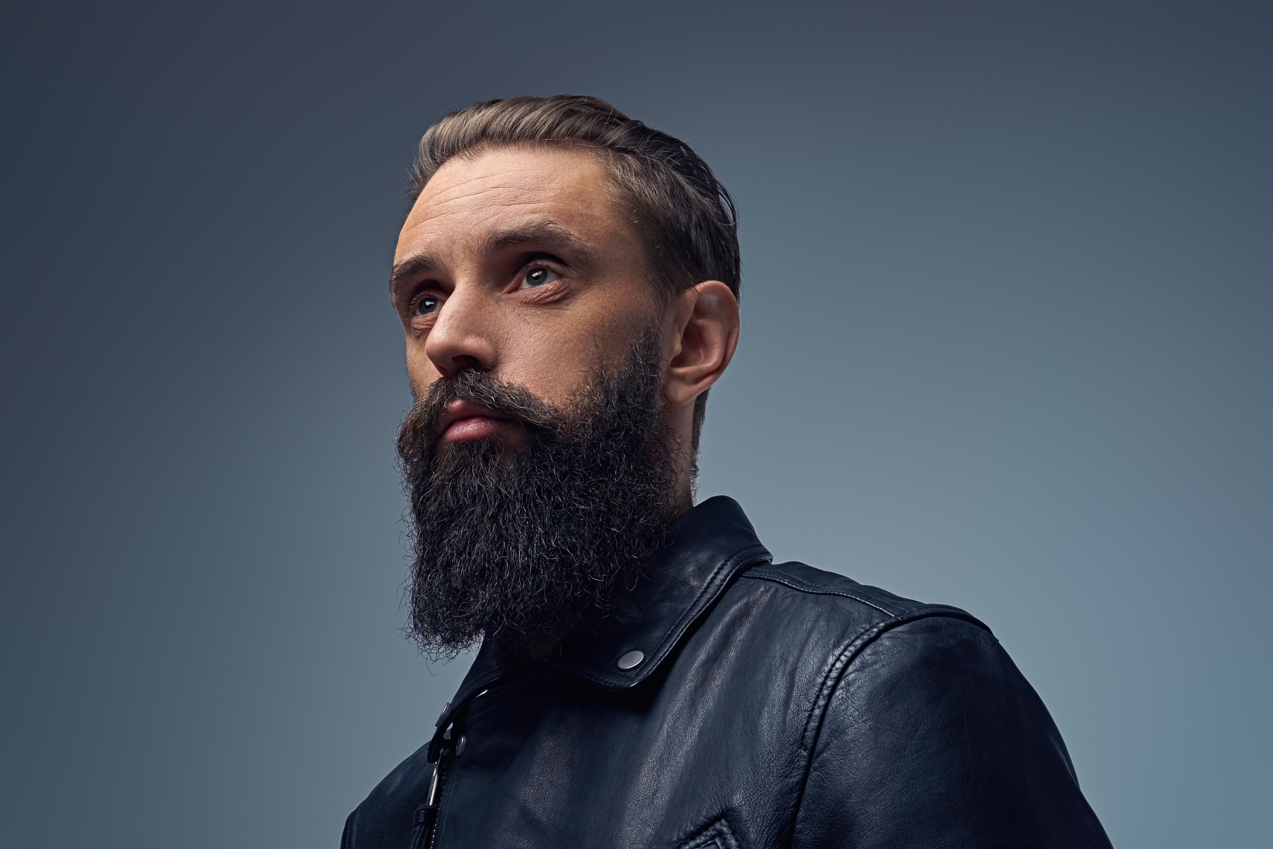 Bearded man in a leather jacket looking upward.