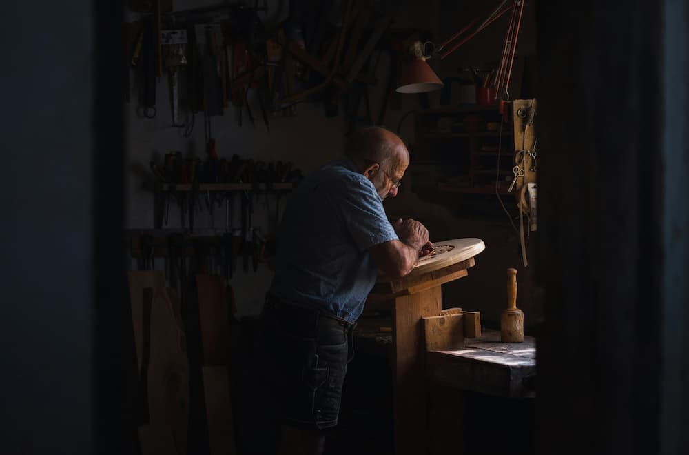 Carpenter working on wood in dimly lit workshop