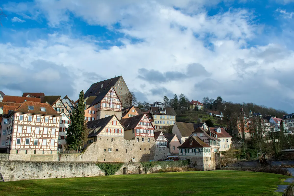 Historische Fachwerkhäuser und Flussufer in Schwäbisch Hall mit Spiegelung im Wasser.