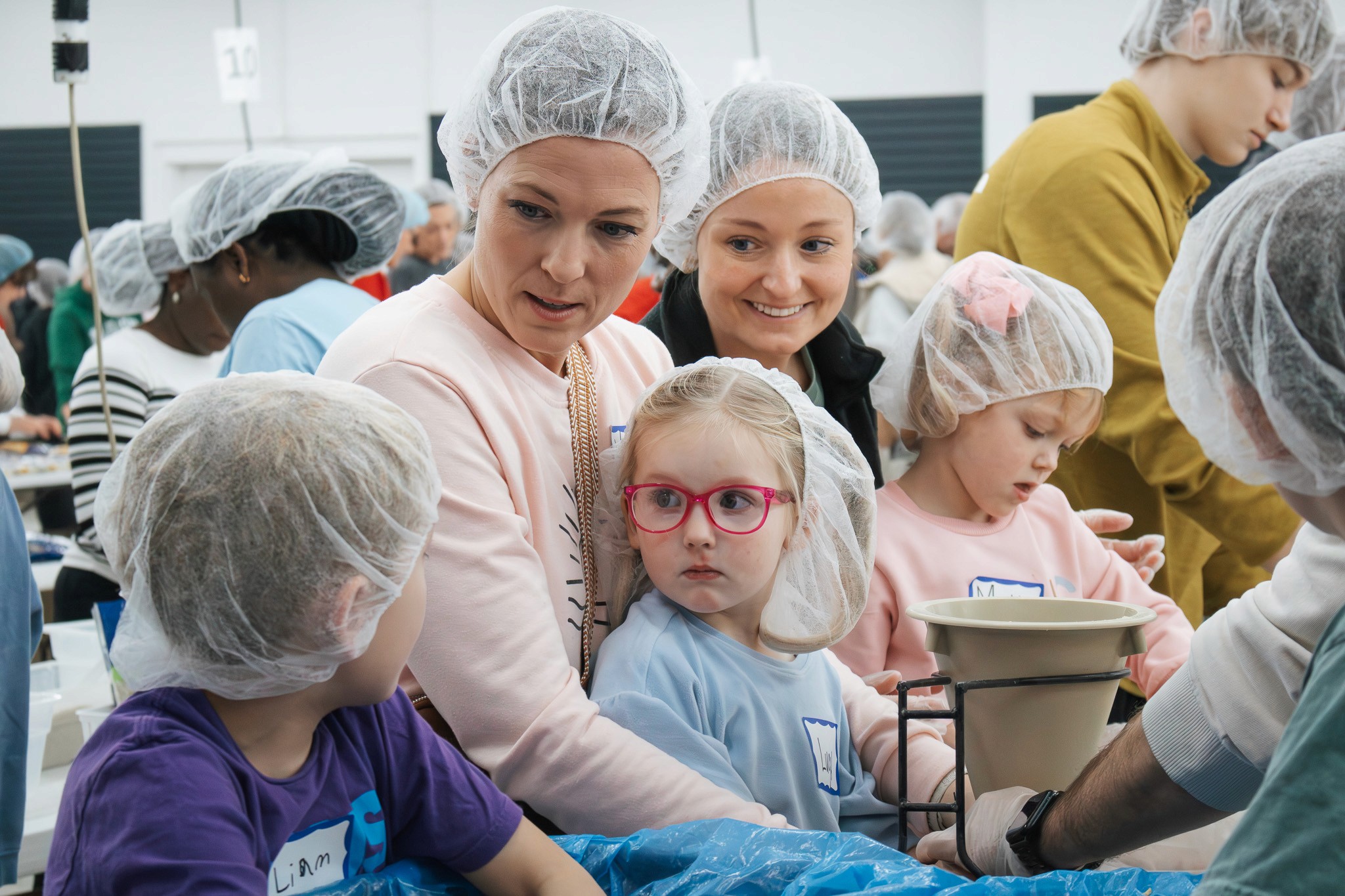 Families and children volunteering together at the Hope Factory in Sharonville, packing meals during a Cincinnati volunteer event.