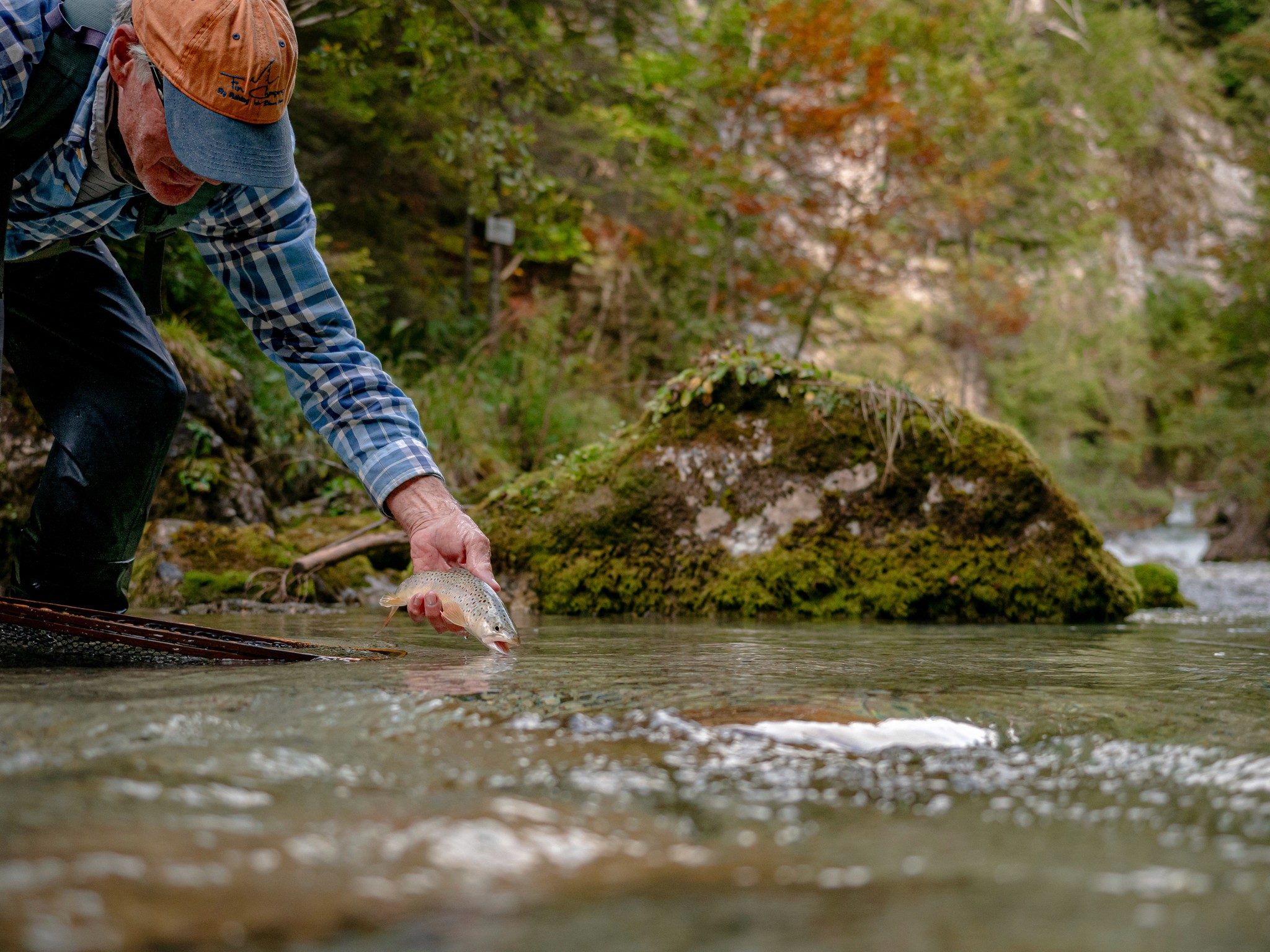 A fly fishing enthusiast casting behind a rock in the Dolomites, combining trekking and fishing in breathtaking nature