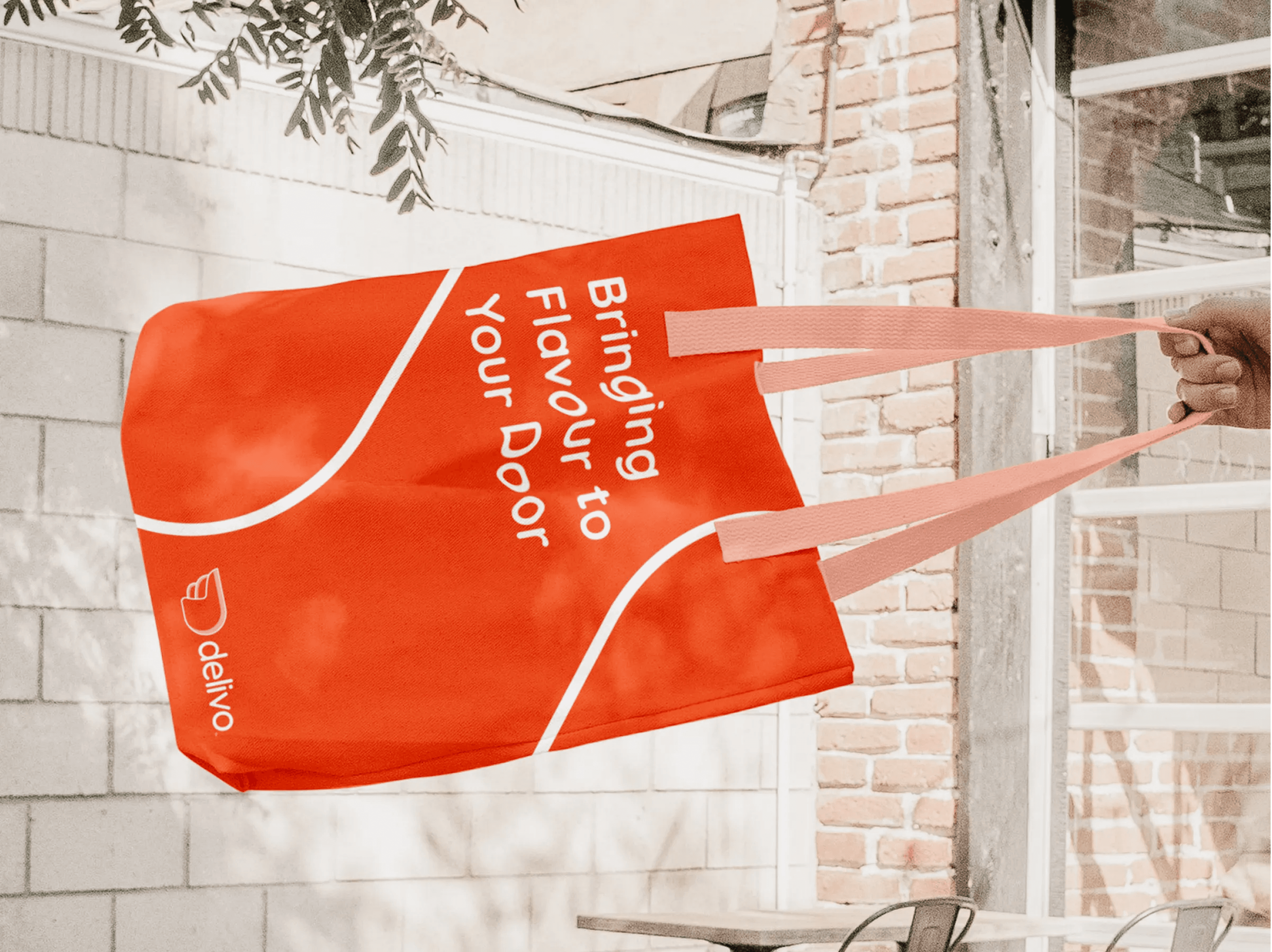 Red-orange delivery bag with white text 'Bringing Flavour to Your Door' and the brand name 'delivo