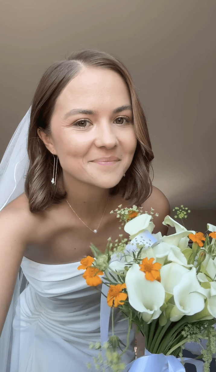 justine de gennes wearing a white wedding dress with flower into her hands