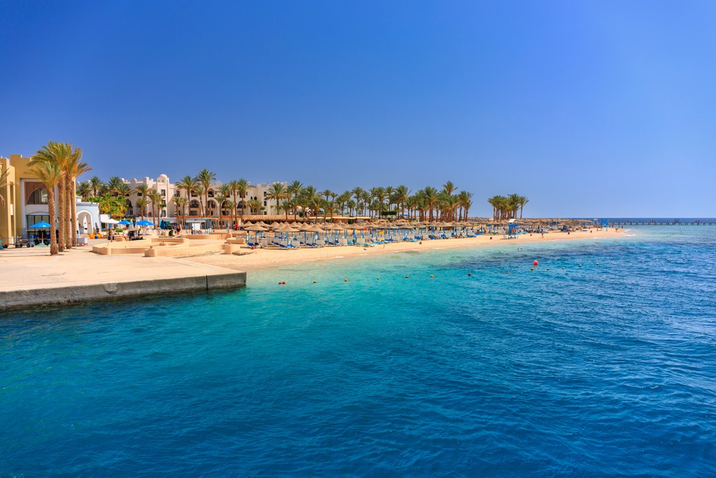A boat traveling down a river next to a beach