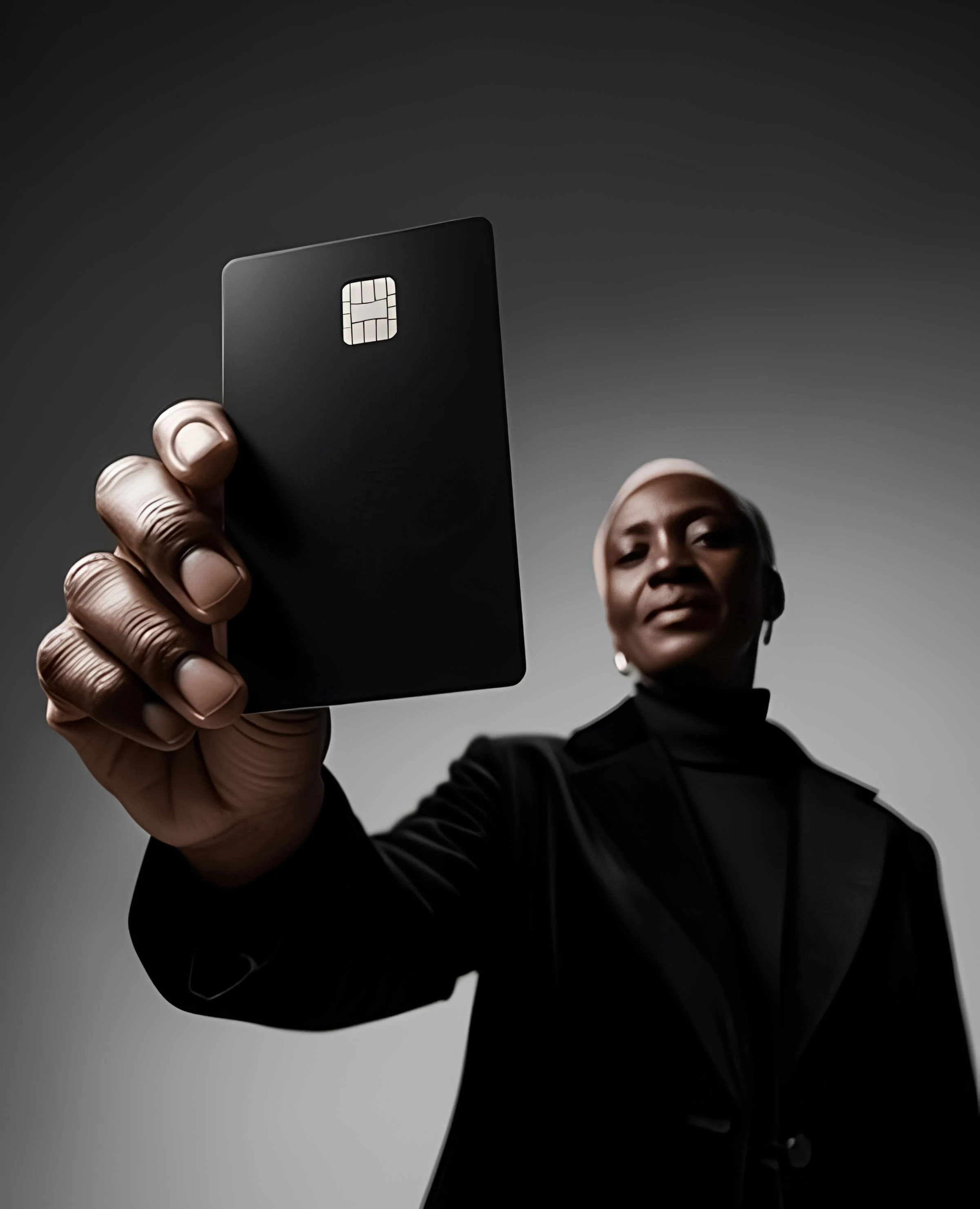 Black woman holds up a black credit card with a chip.