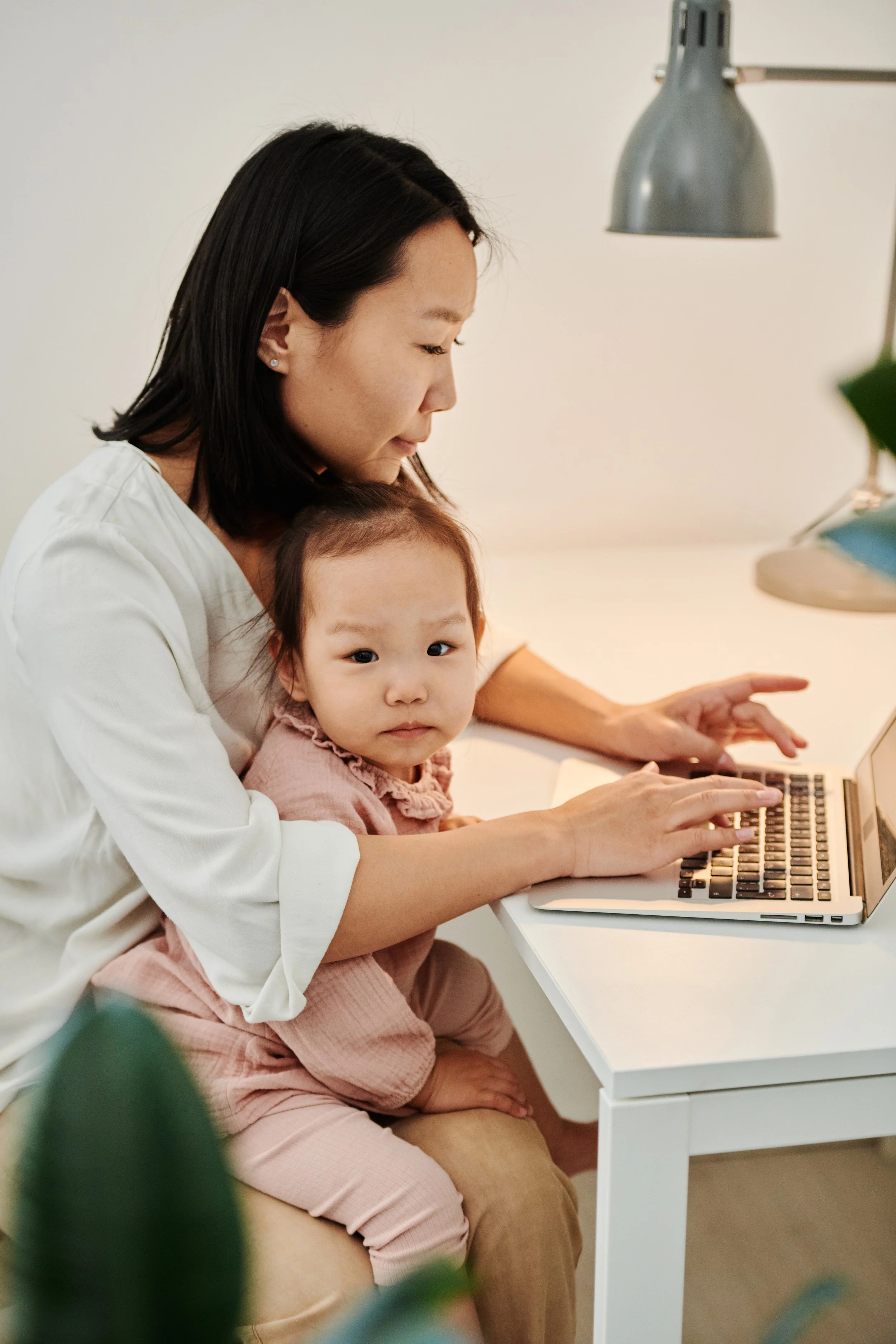 A mother sits with her child on her lap while working