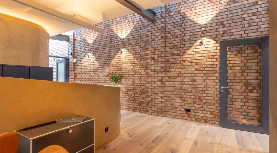 Modernes Büro-Interieur mit Backsteinmauer, Holzboden und Beleuchtung. Architekturbild.