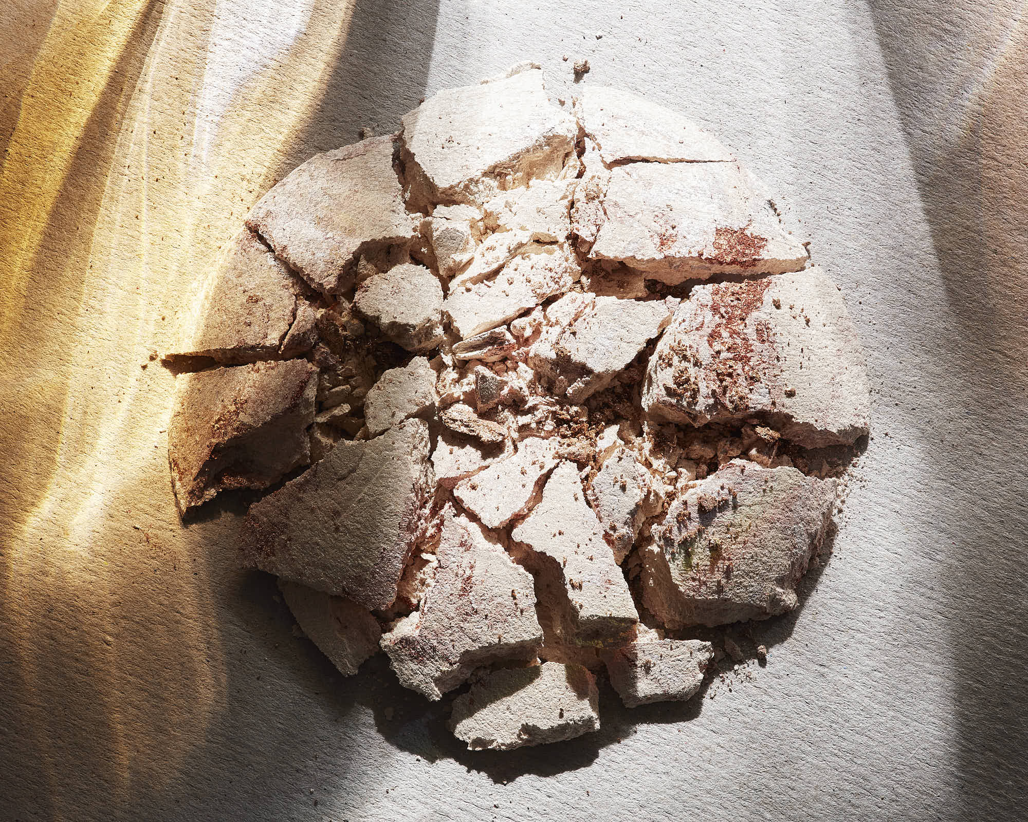 A round, cracked surface resembling textured stone, illuminated with soft lighting and surrounded by warm colors.