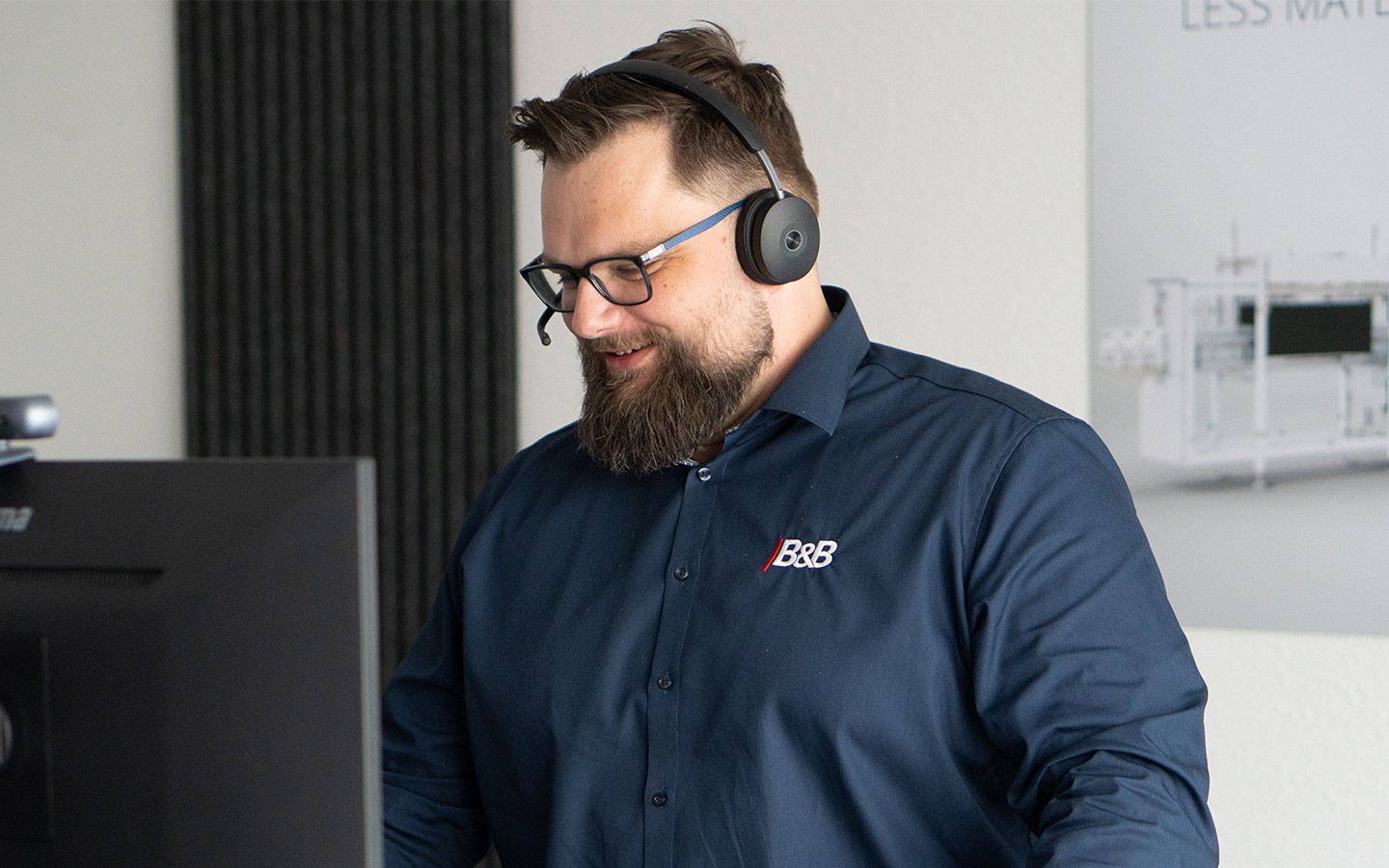 Mann mit Headset und Brille bei der Arbeit am Computer. Online Meeting oder Kundenservice.