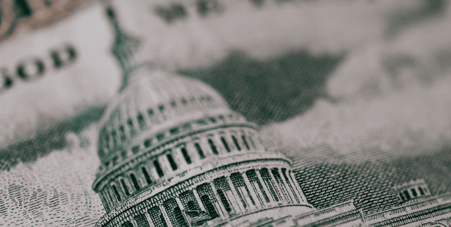A close-up of the U.S. Capitol building with a cloudy sky in the background, presented in a black-and-white style.