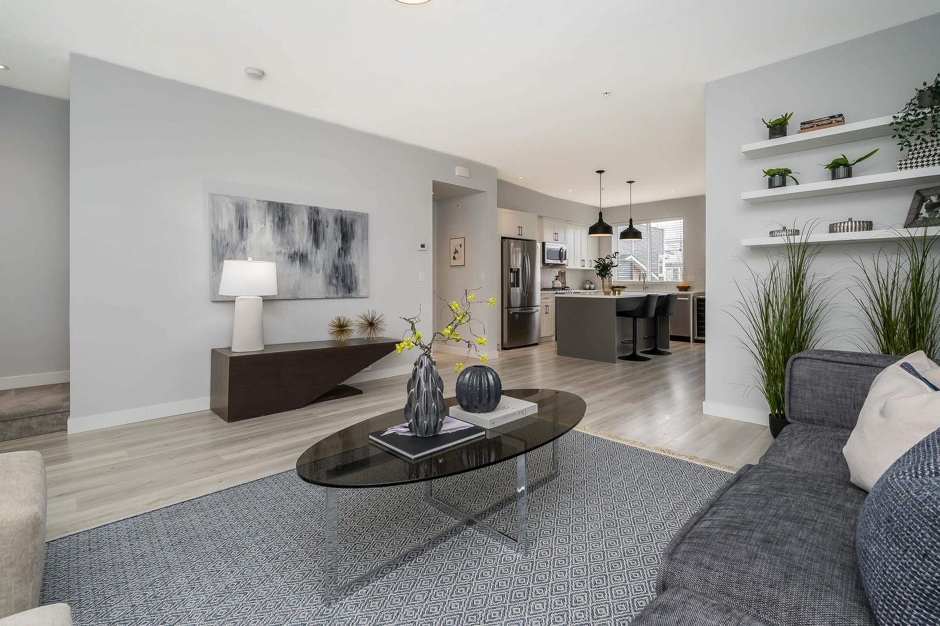 A modern living room featuring a grey sofa, coffee table, and stylish decor in a light-colored space.