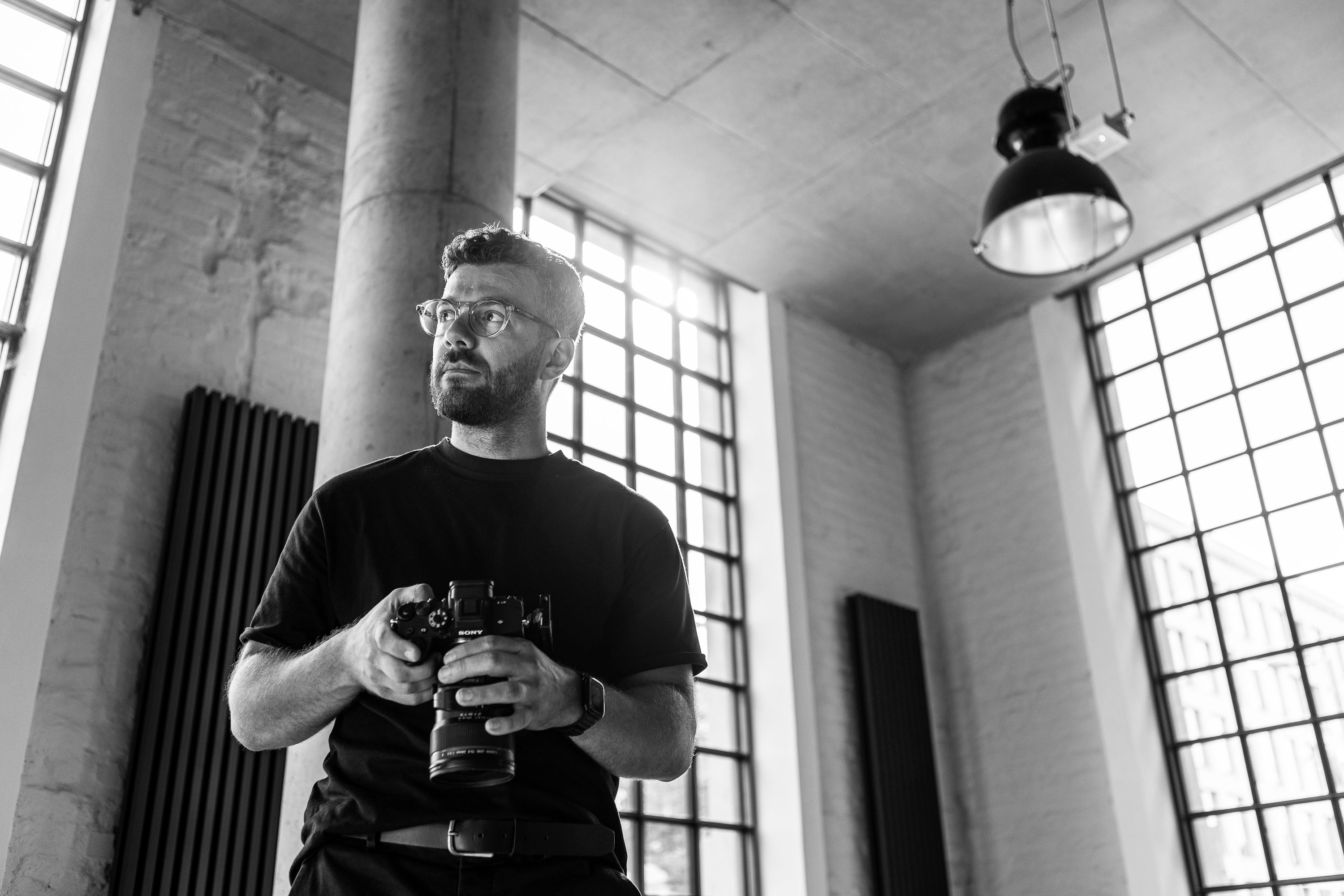 Portrait of a Prague-based conference photographer holding a camera in a studio setting.