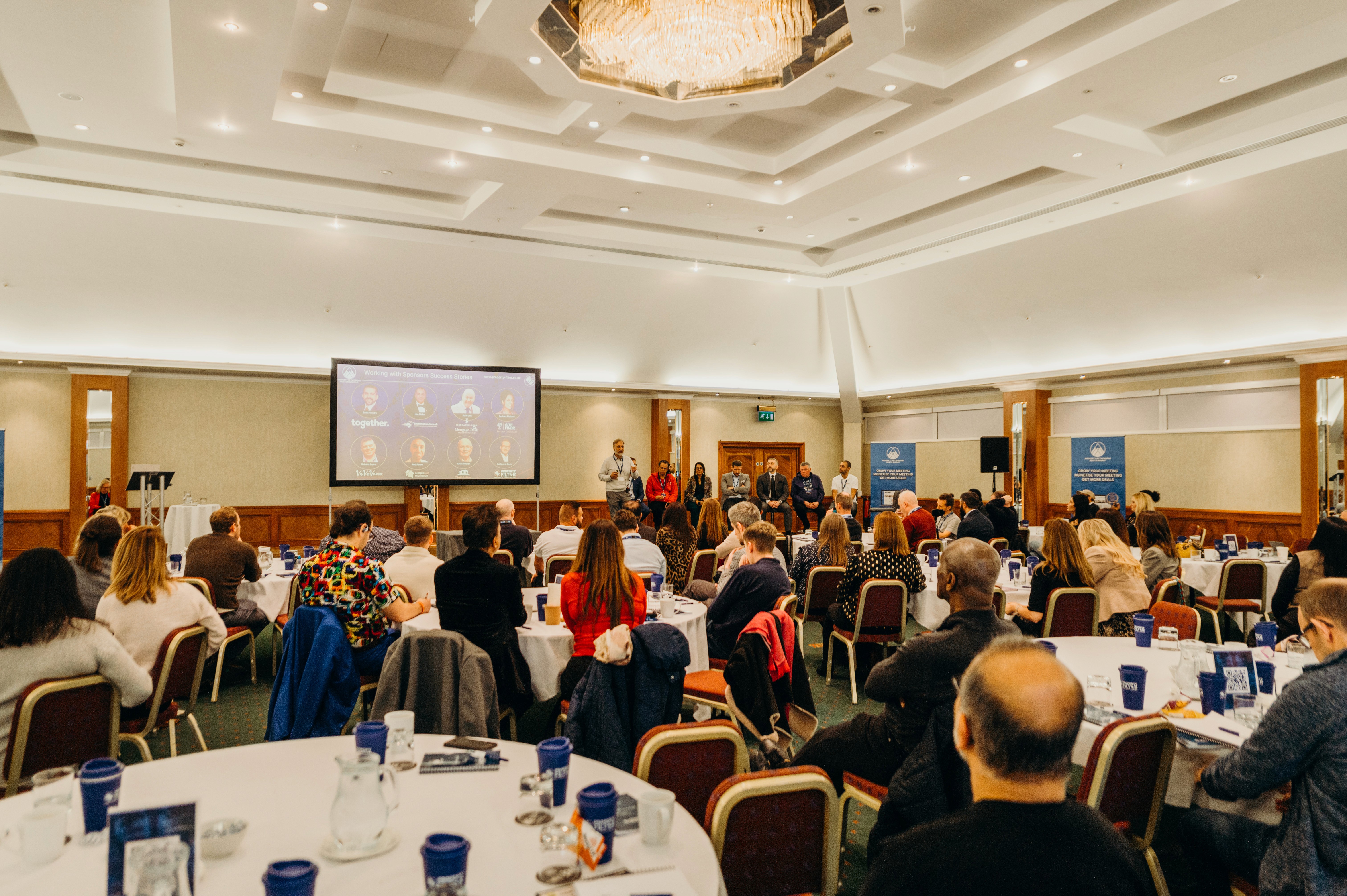 Victorian terraced houses in London featuring elegant period architecture with ornate iron balconies, white stucco ground floors, exposed brick upper levels, sash windows, decorative columns, and manicured topiary trees on the balconies, showcasing classic British residential architecture