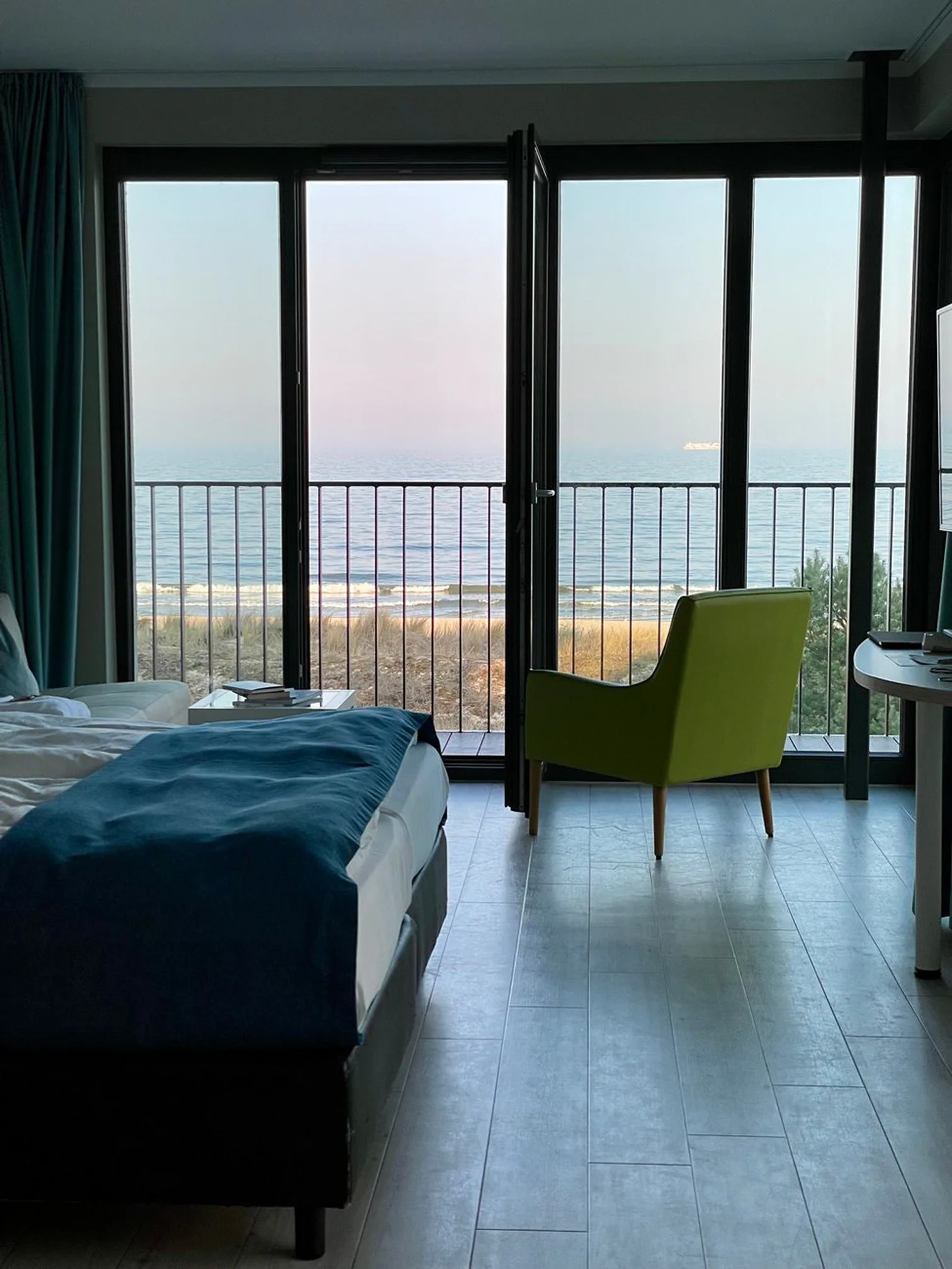 Beachfront bungalow bedroom with large glass doors, sea view, and a cozy sitting area.