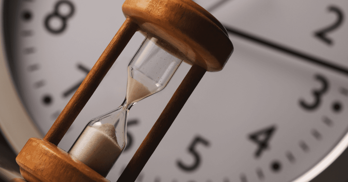 Tall grasses or reeds silhouetted against a hazy, golden sunrise or sunset.