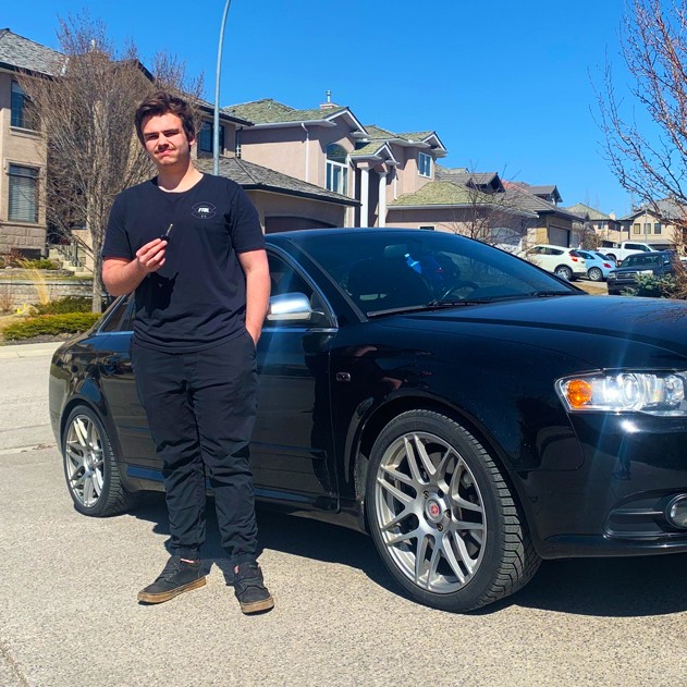 happy audi customer holding new car key made by carkeyaction beside his car