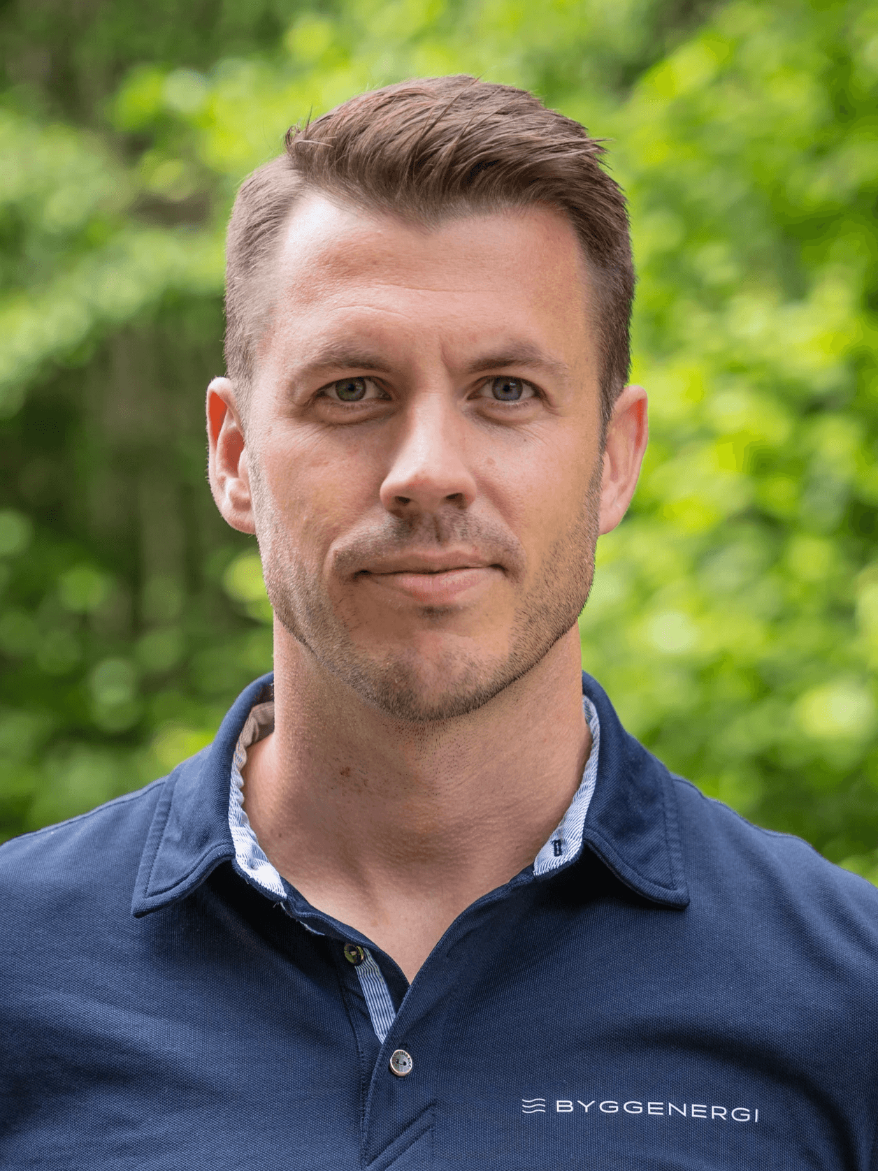Mann i blå skjorte med Byggenergi logo foran et tre