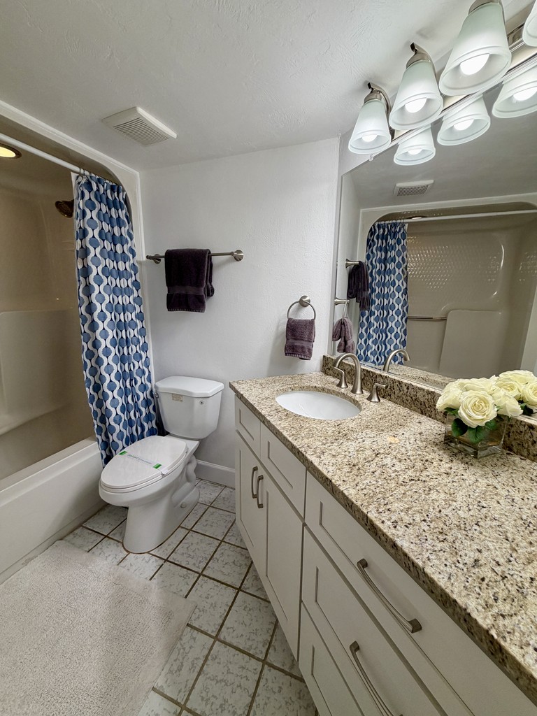 Bathroom with a granite vanity and shower curtain, Unit 602 at Oceans Atrium, a vacation rental in Daytona Beach Shores