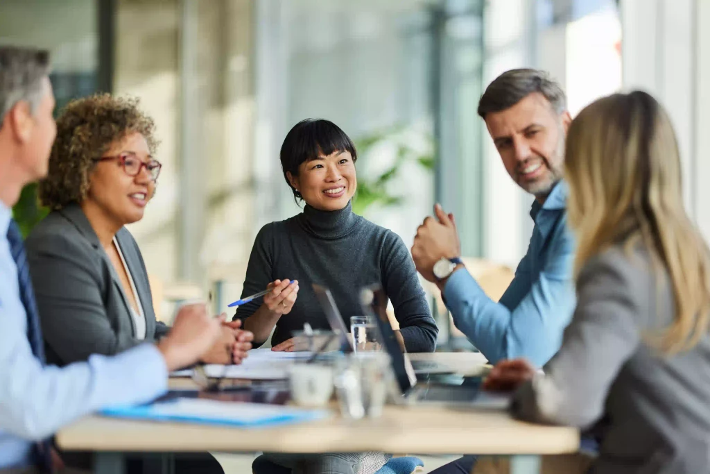 Group of colleagues sharing a friendly conversation in a meeting room, emphasizing the value of teamwork and strong relationships.