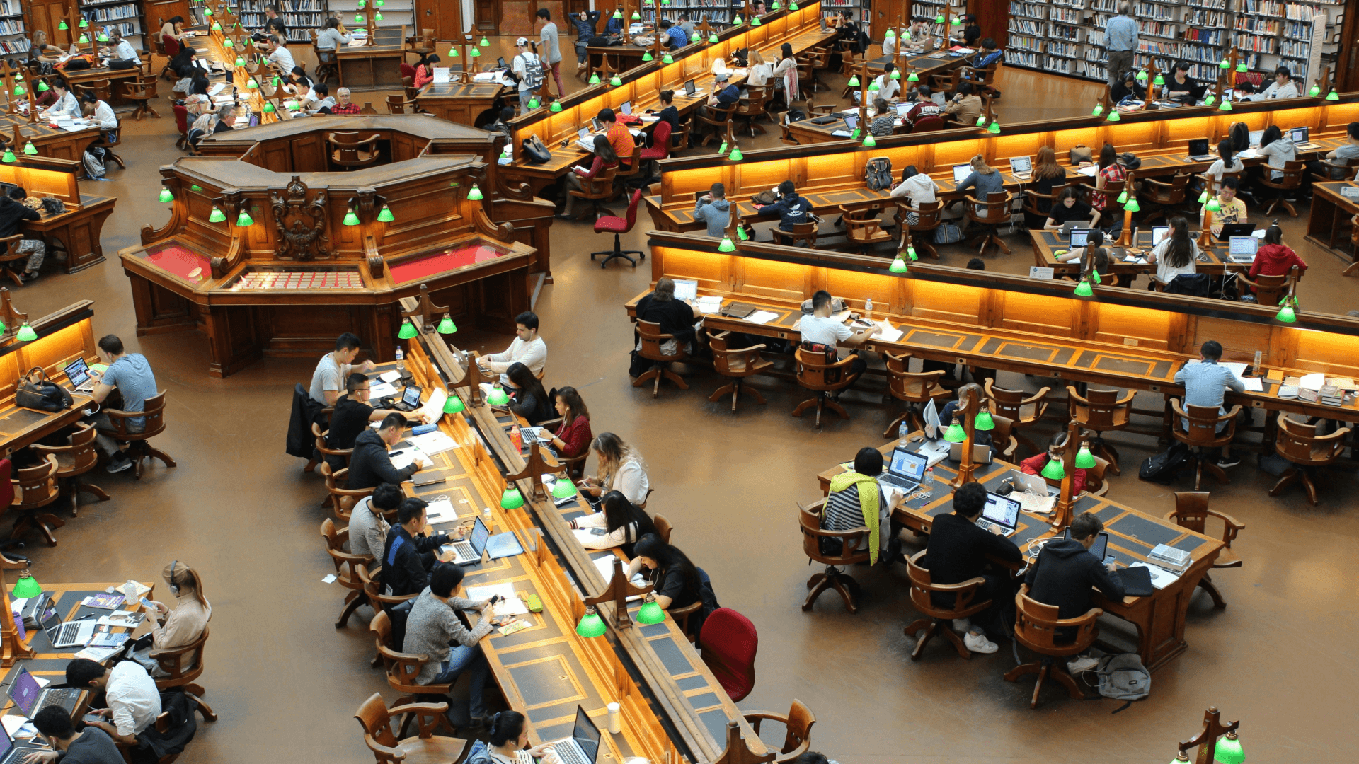 A large hall filled with people working on laptops, representing collective learning, upskilling, and the role of human capital in adopting AI at scale