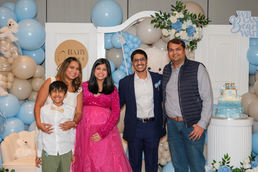 Family posing beside blue balloon decor at a celebration