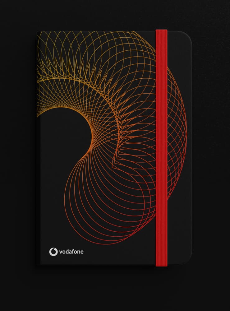 Black branded notebook featuring the custom 'network topology' gradient pattern in Vodafone Red and orange, designed as internal culture merchandise.