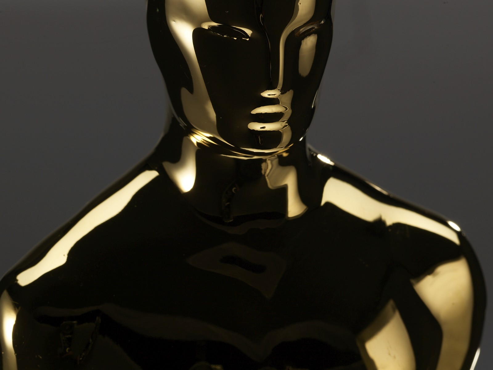 Close-up of an Oscar statuette’s head and shoulders, gold-plated and reflective against a dark background, used as a header image for an essay about awards season, meaning, and marketing craft.