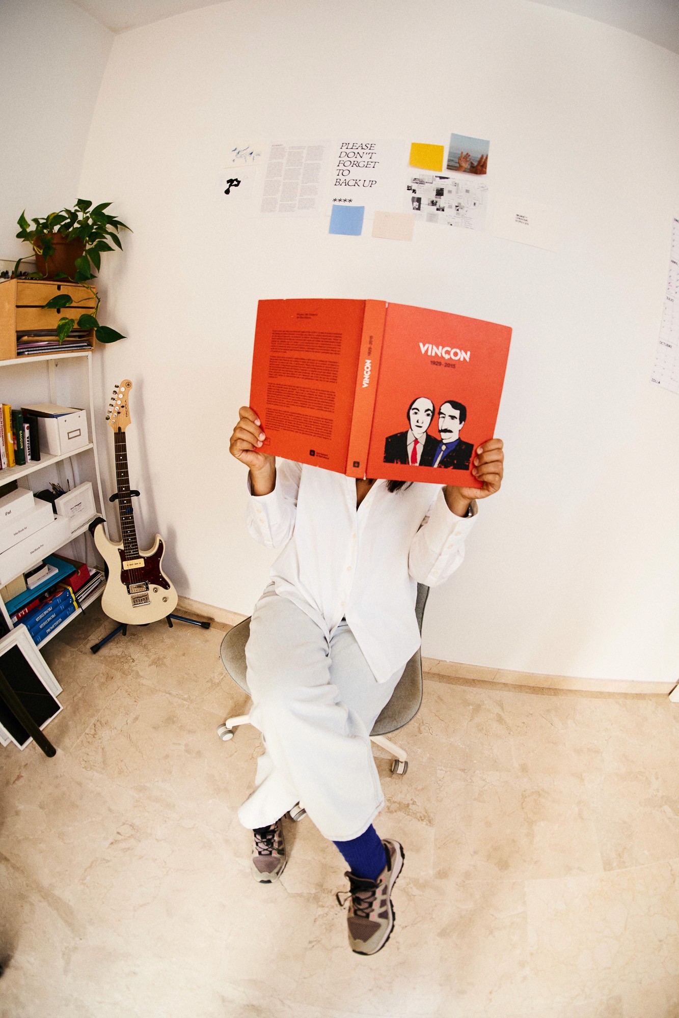 Flor Pérez playfully covering her face with a large orange book