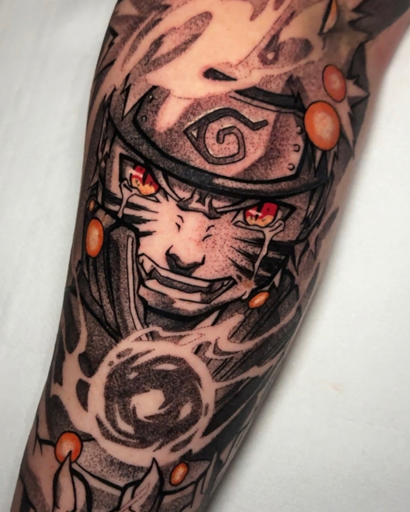A grayscale anime-style tattoo of a character with spiky hair and a headband, holding a kunai.  The tattoo is on someone's forearm.