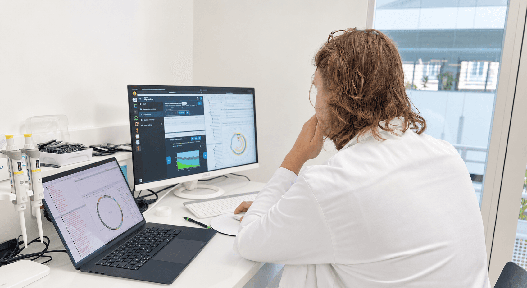 Neoplants scientist reviewing sequence designs, computational models and experimental data at a laboratory workstation.