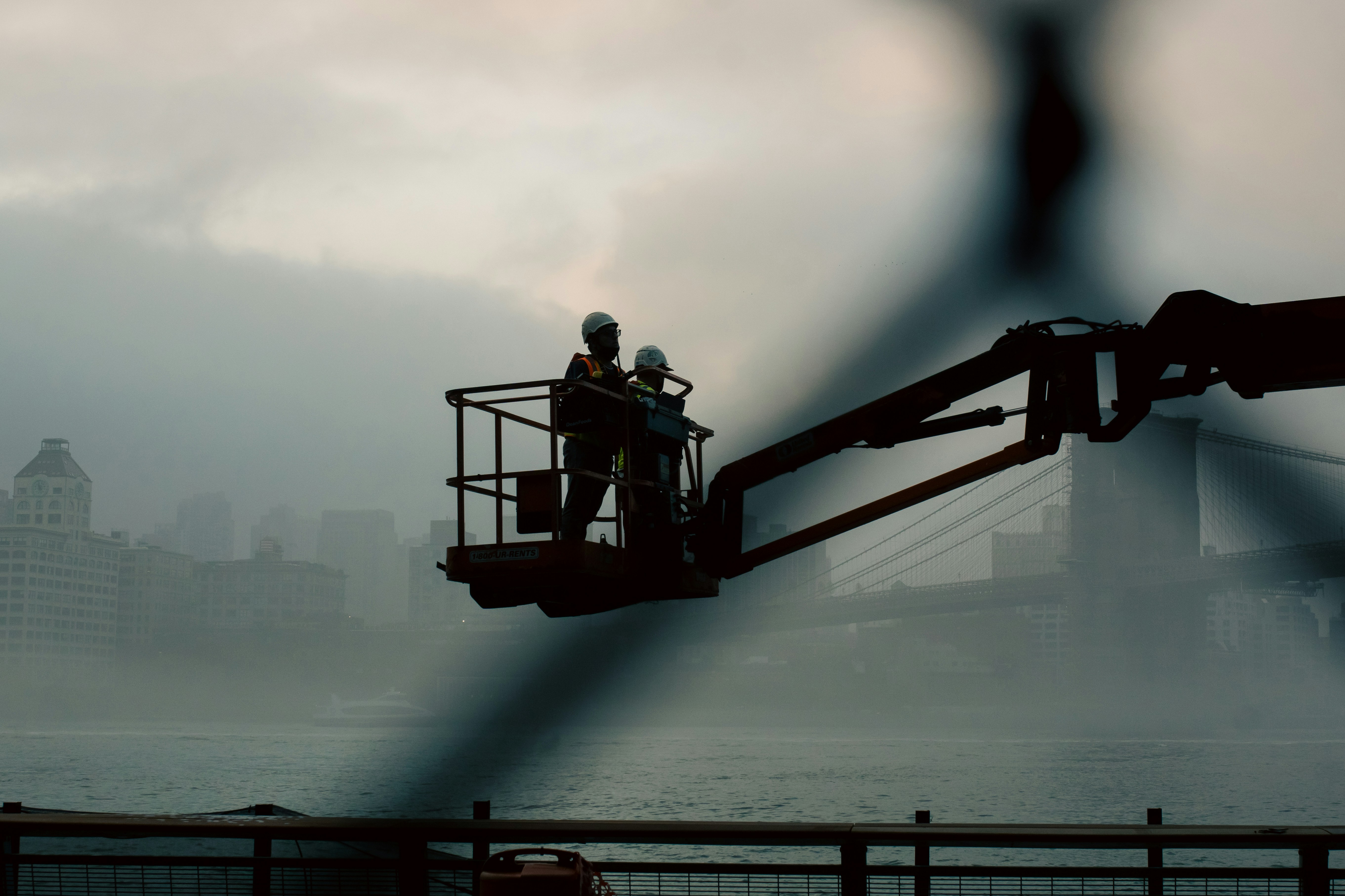Two construction workers in a lift overlooking city