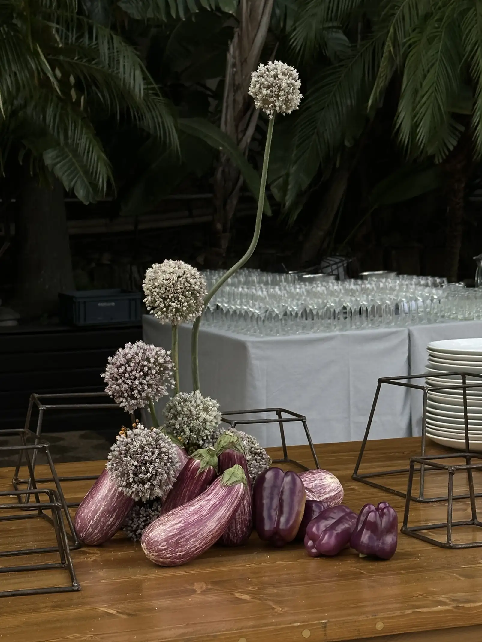 Centro de mesa con berenjenas y flores lilas para propuesta floral experimental, fusionando lo orgánico y lo gastronómico en diseño artístico.