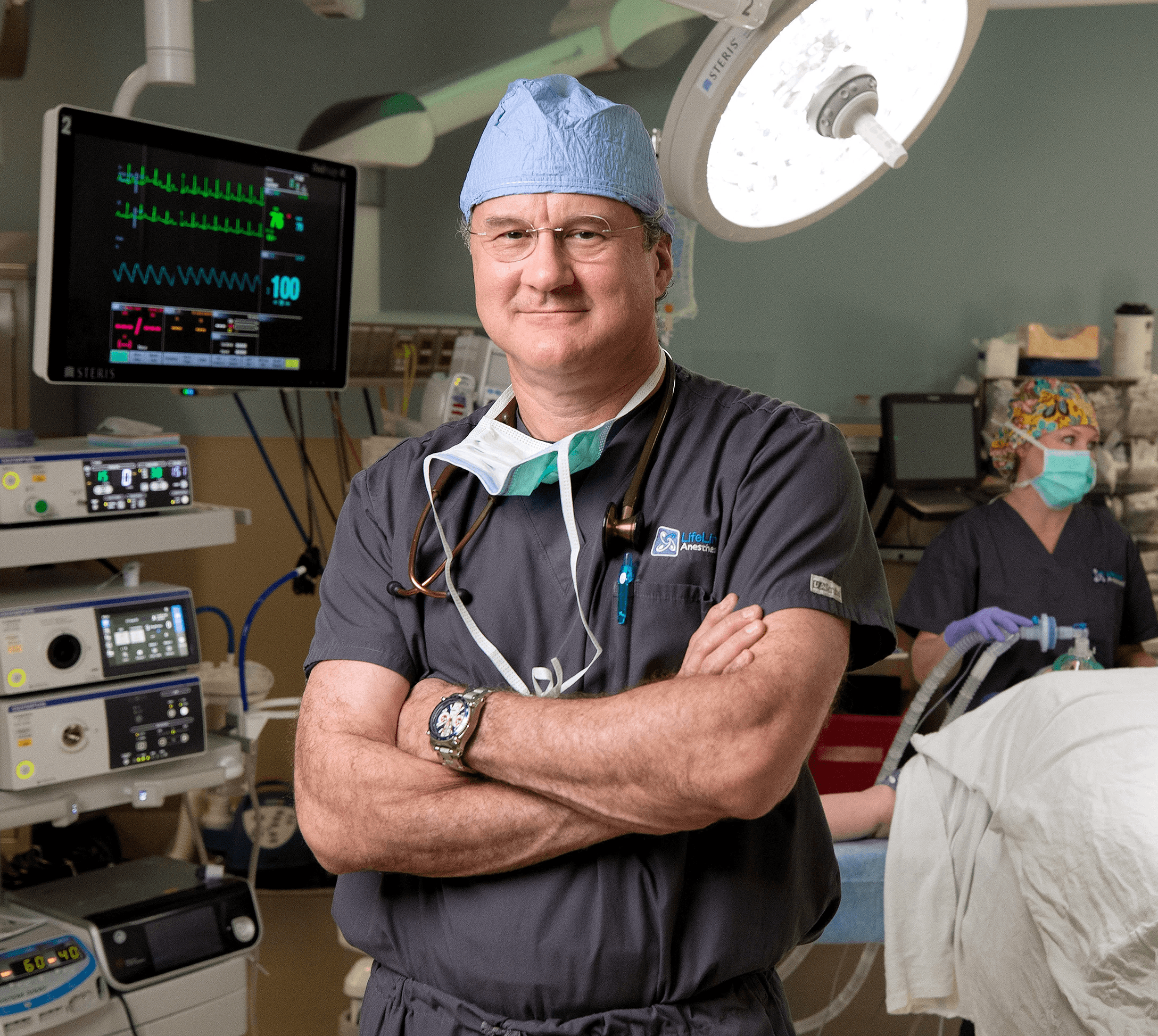 LifeLinc anesthesiologist in scrubs with OR monitoring equipment in background