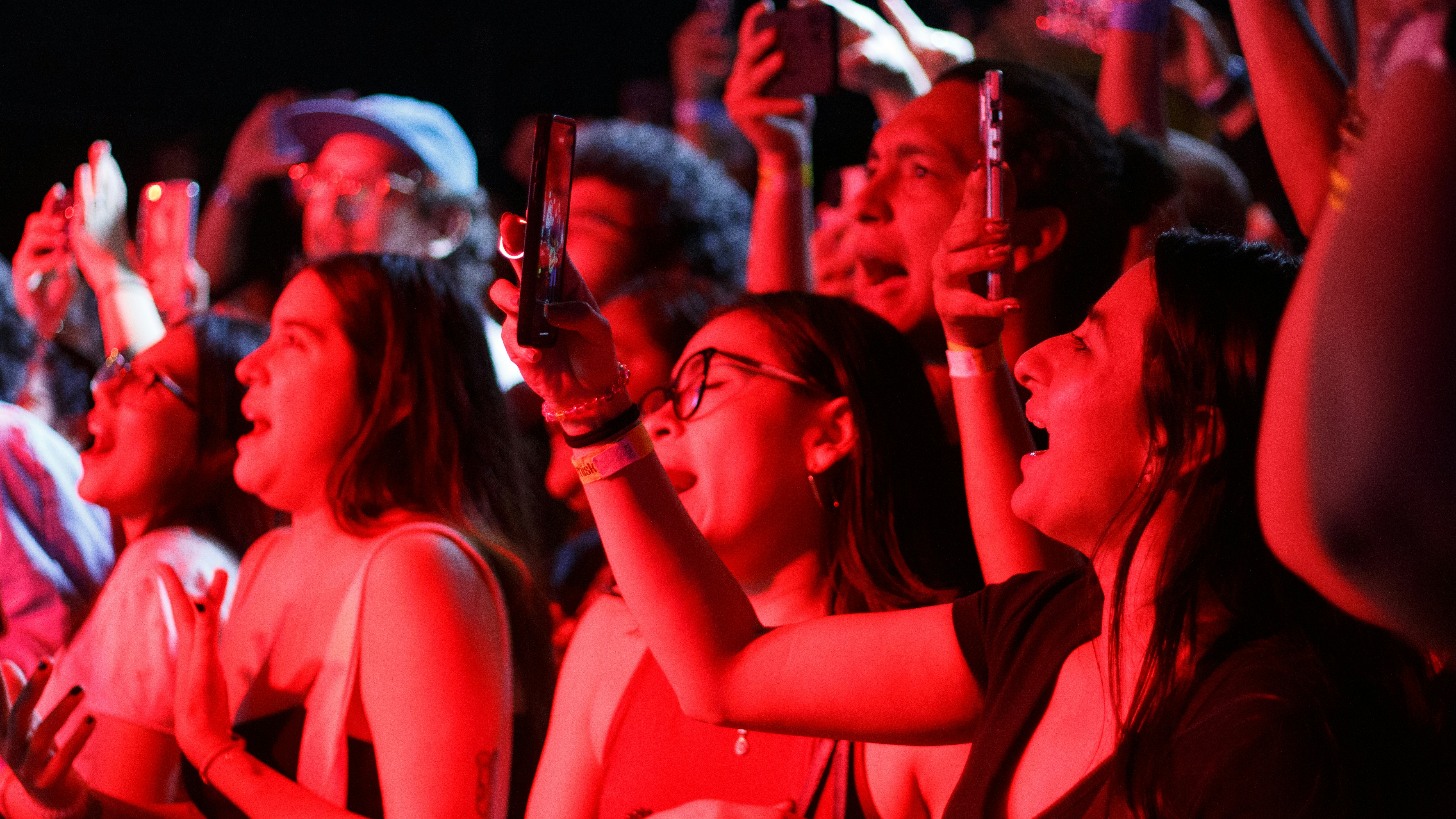 A crowd in a concert cheeting and filming the show. Photo by Les Taylor on Unsplash