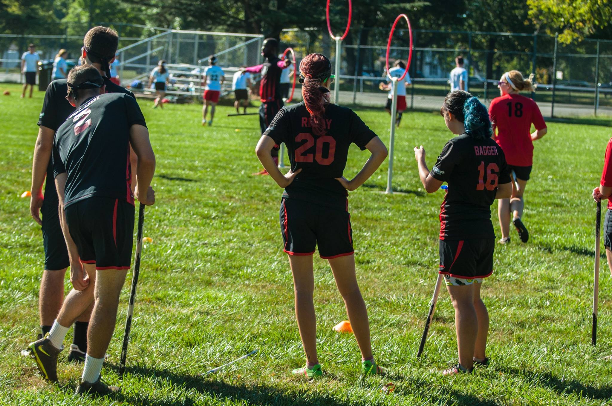 Quadball players with red and blue hair stand on the sideline