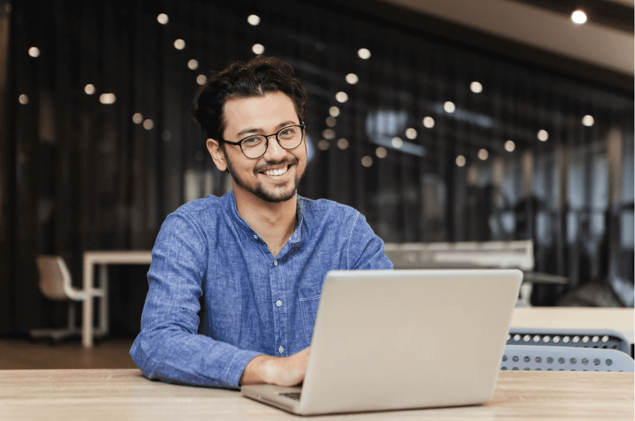 Smiling Amazon seller working on a laptop in a modern office — representing streamlined, automated Amazon ad management at scale during Q4.