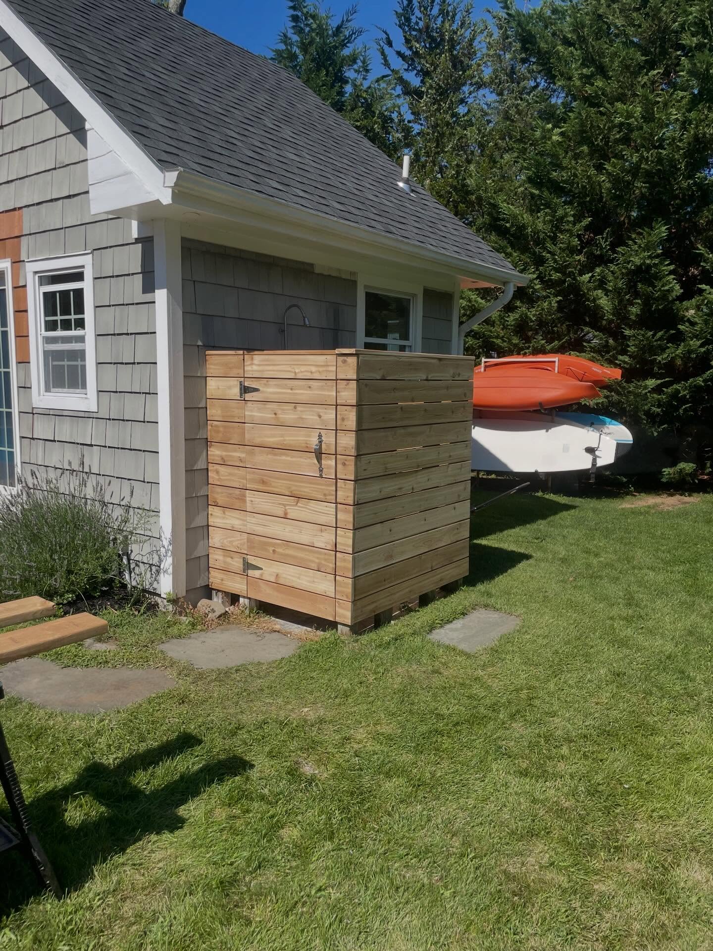 New cedar outdoor shower enclosure built against shingled house
