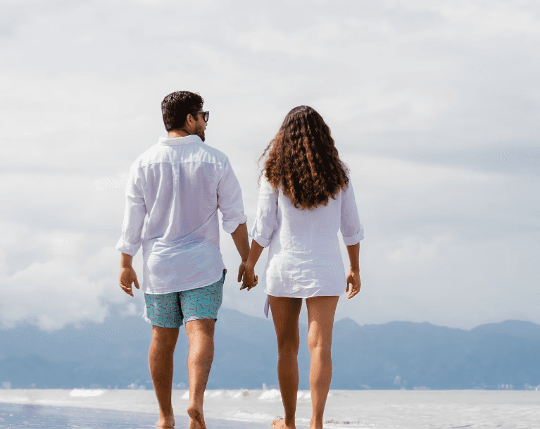 A circle of people sitting cross-legged, meditating with hands in a prayer position. Soft, warm lighting.