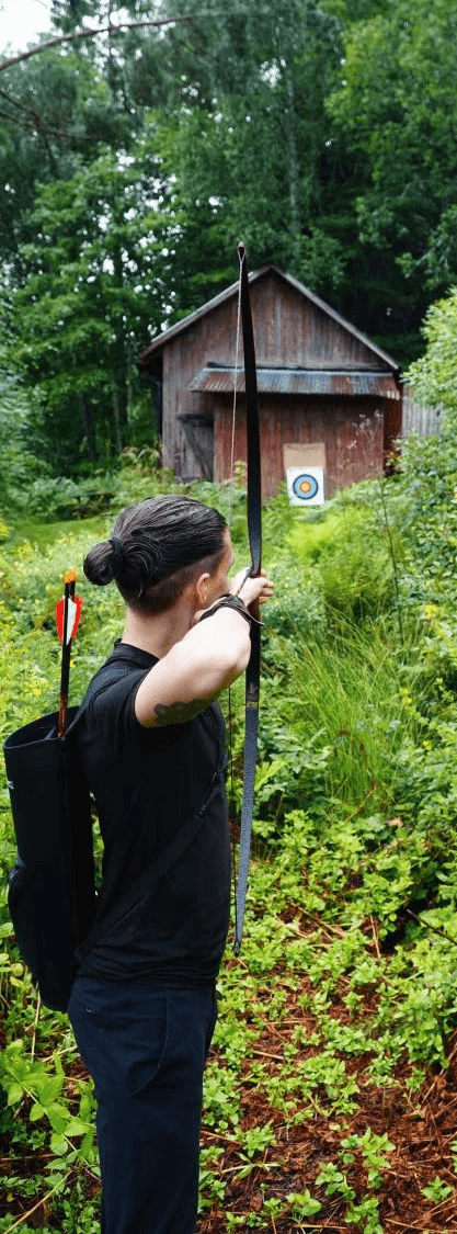 Person practicing archery in a forest, aiming toward a distant target — symbolizing focus and clarity.