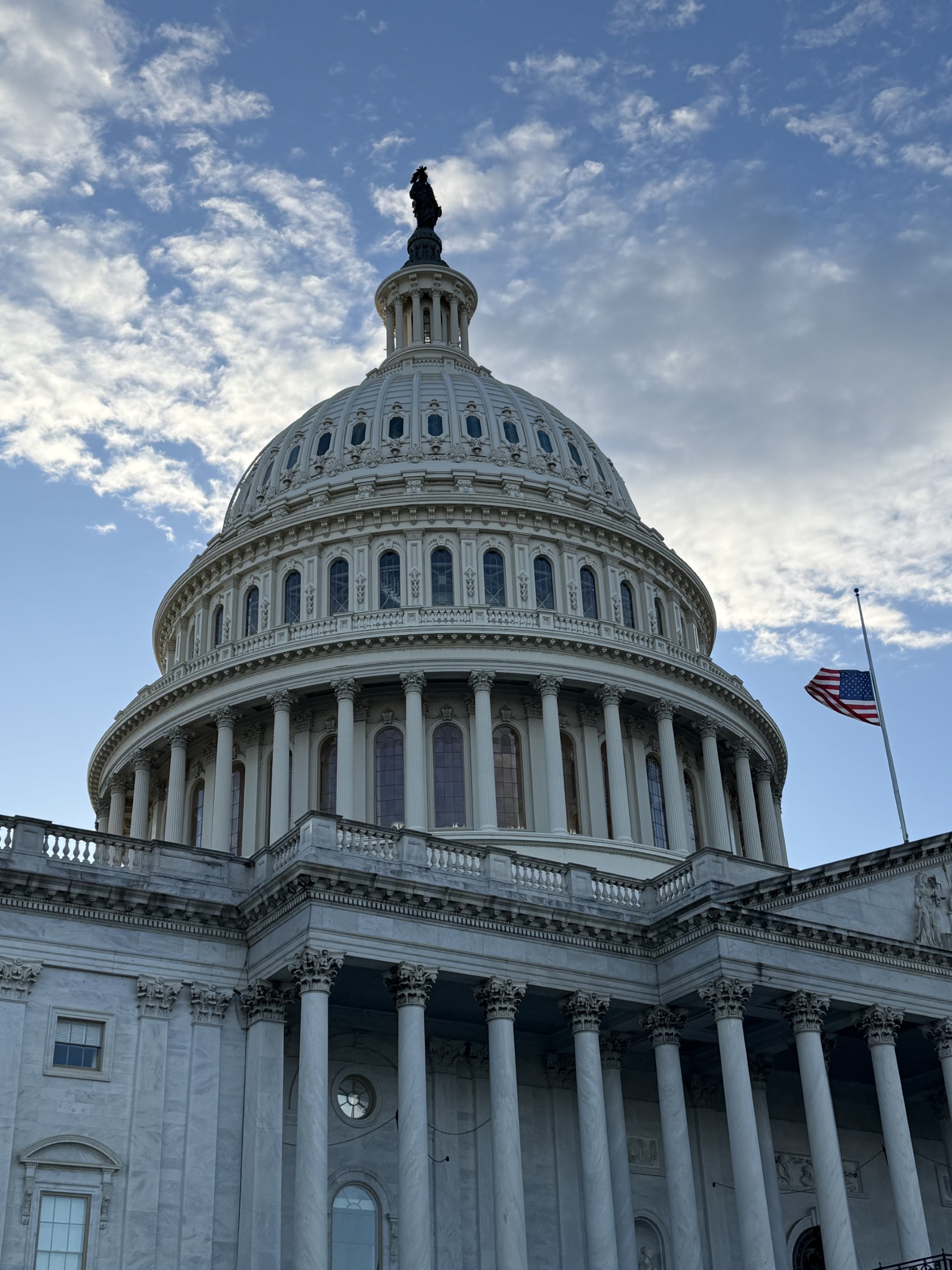 Low angle view of a modern white and orange building under the bright sky