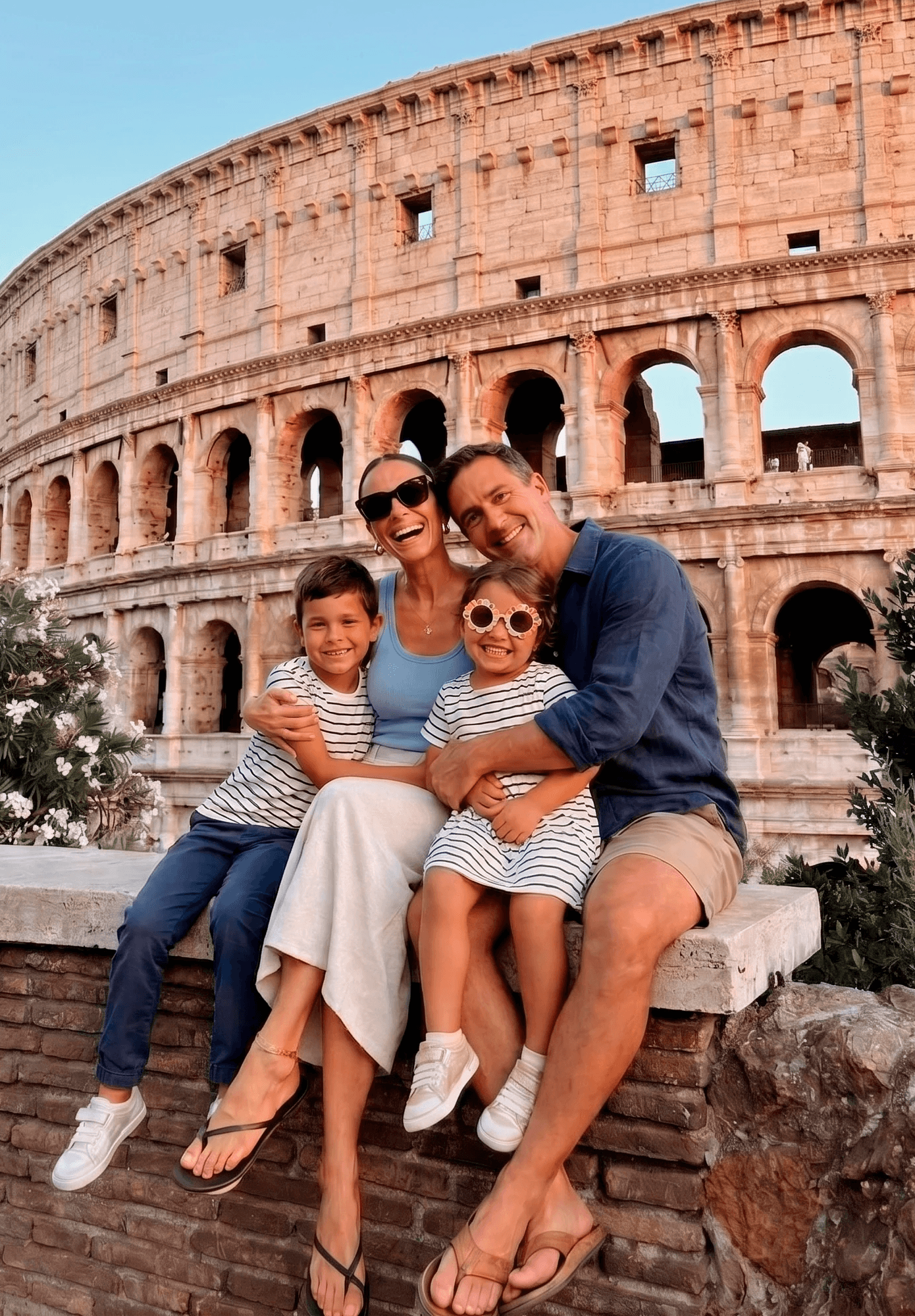 Persona joven de pie posando con unos tenis Adidas blancos frente a un fondo neutro, mostrando el calzado de perfil.