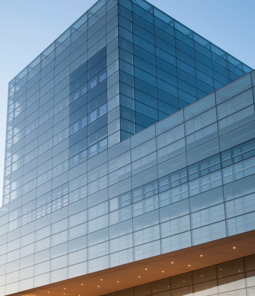 A modern glass building with a spacious glass front, reflecting the surrounding cityscape.