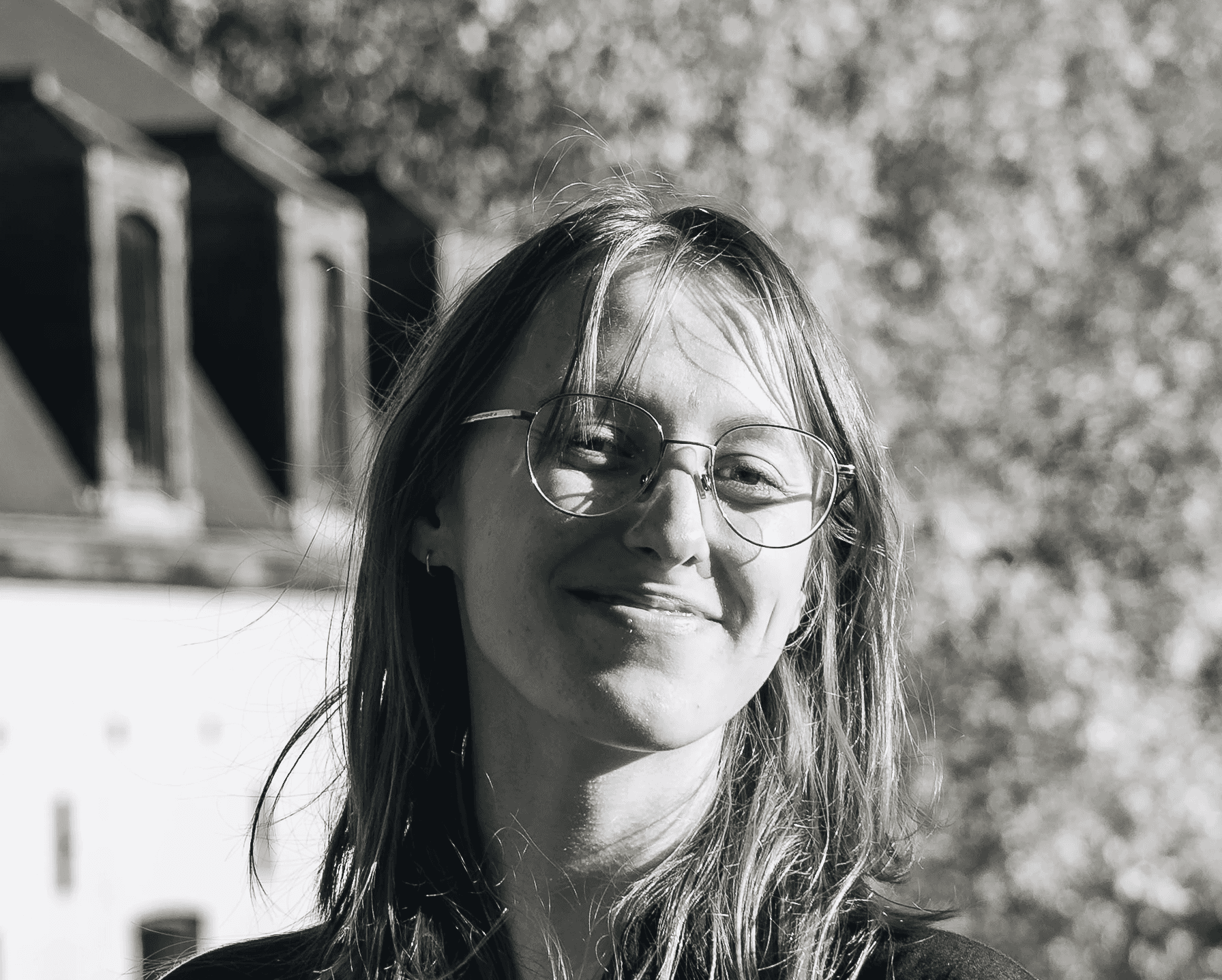 Portrait of a laughing person with curly hair wearing a white shirt