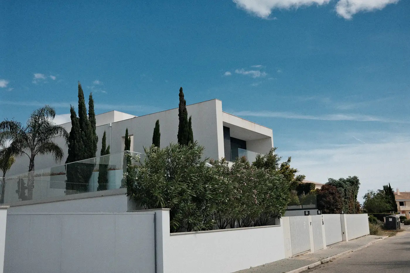 Modern white house with cypress trees and blue sky