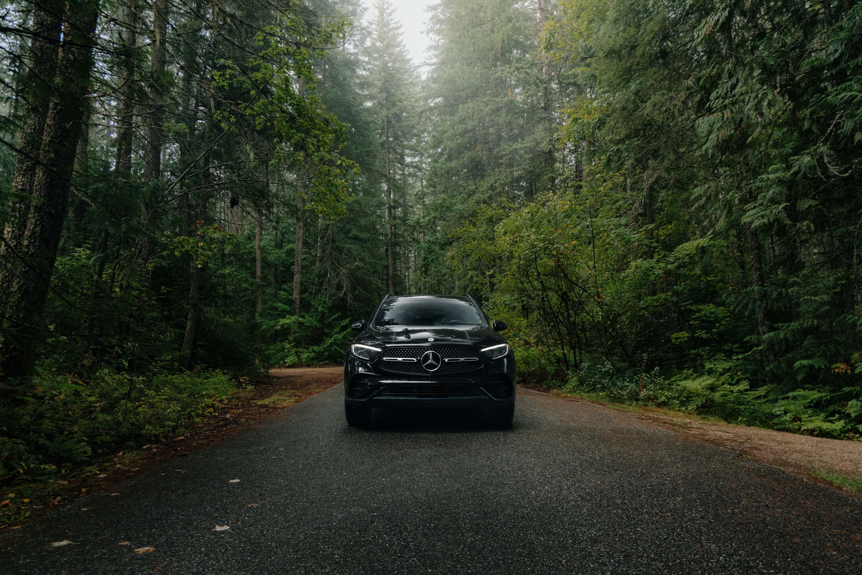 Black Mercedes-Benz GLC on a gravel shore beside a turquoise lake in British Columbia
