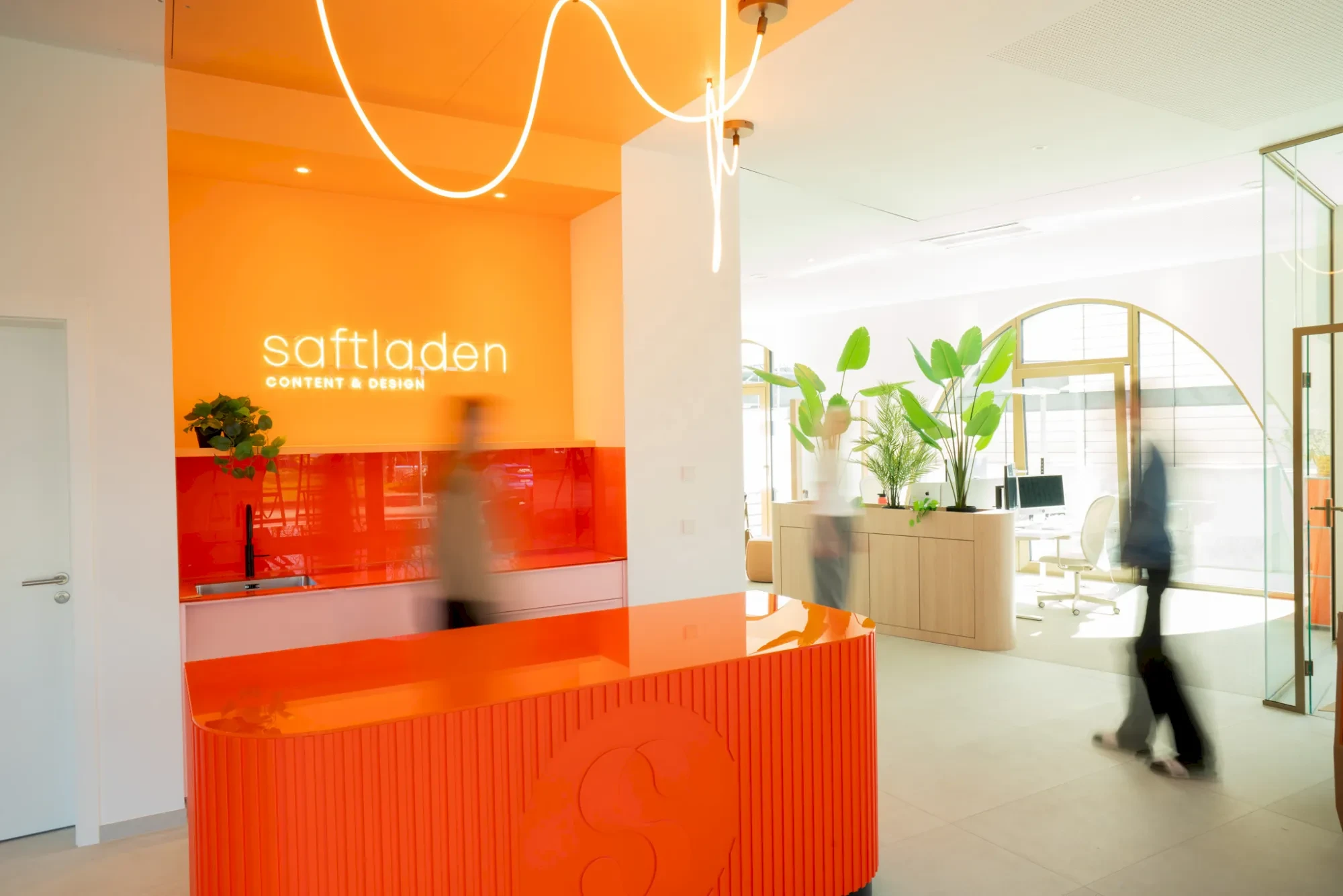 Orangefarbener Empfangsbereich von Softladen. Modernes Design mit Büropflanzen & Beleuchtung. Büro