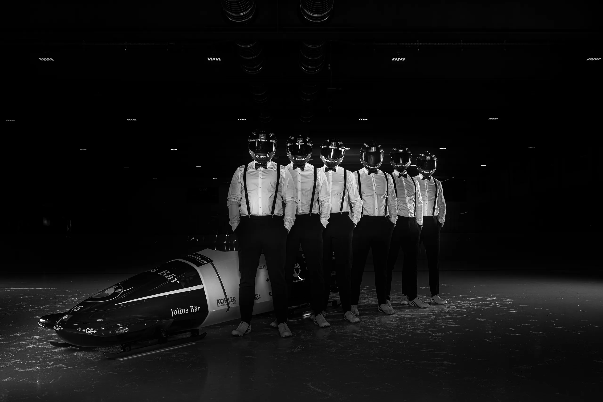 Creative group photo of Bobteam Vogt wearing formal suits and racing helmets.