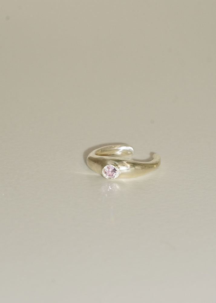 Silver ring with a pink gemstone on a light gray background
